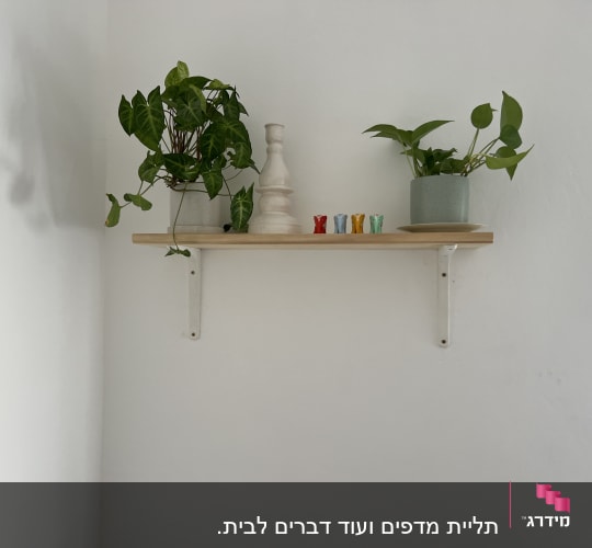 מדף עץ עם תומכים מתכתיים על קיר לבן